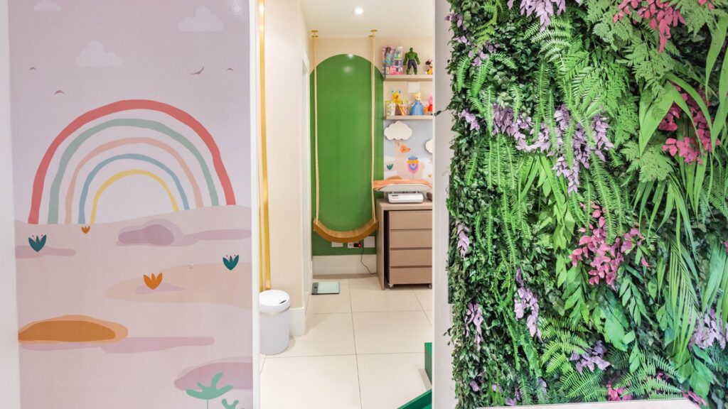 Ambientes do consultório: parede com arco-íris, sala infantil e parede de plantas
