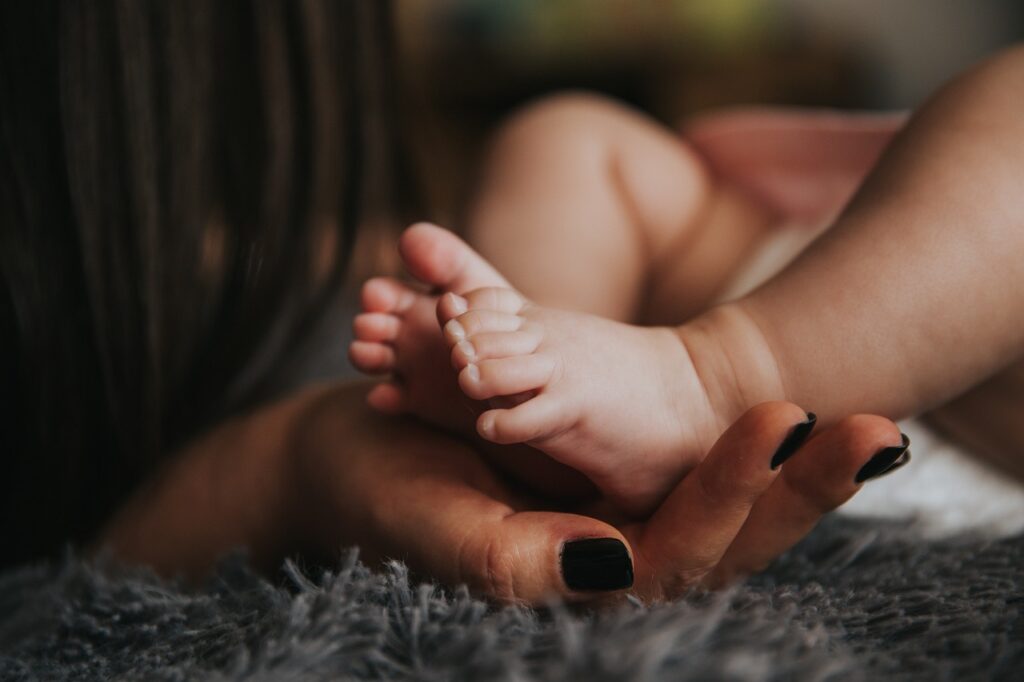 Mae segurando os pes do bebe, cuidado com a pele, tema dermatite atopica infantil