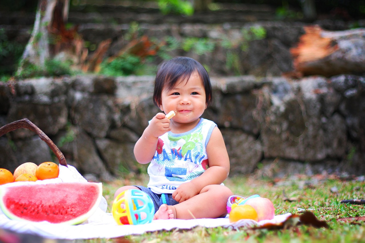 Crianca pequena comendo frutas ao ar livre em piquenique, tema de alergia alimentar infantil