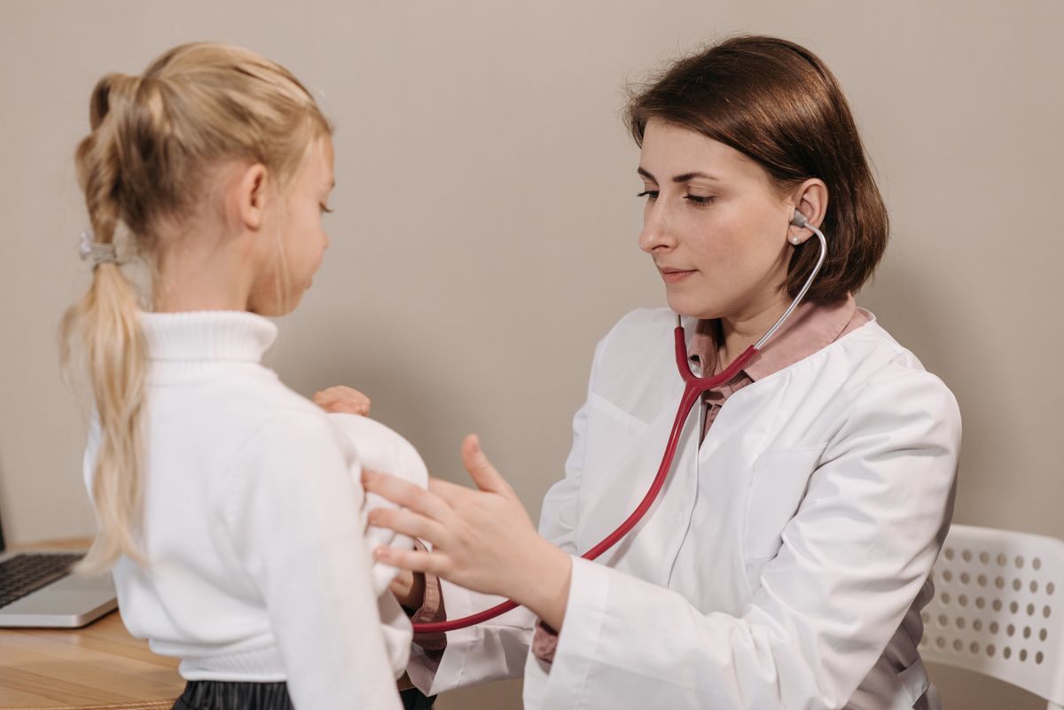 Pediatra examinando criança com estetoscópio, ilustrando o artigo sobre urticária infantil