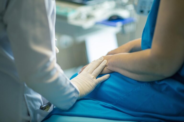 Mão do médico apoiada no braço do paciente durante avaliação em consultório