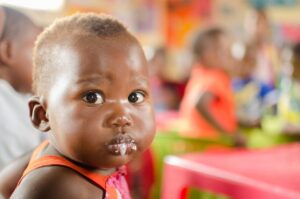 Criança pequena com comida parada na boca durante a refeição